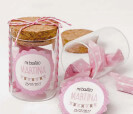 Tarro de cristal con caramelos adornado con pegatina personalizada en color rosa como detalle para bautizo